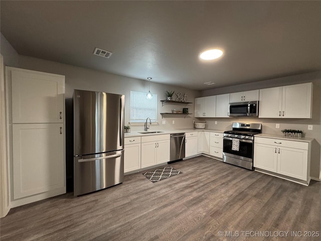 kitchen featuring appliances with stainless steel finishes, sink, white cabinets, and dark hardwood / wood-style flooring