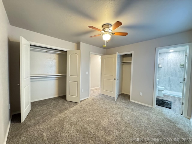 unfurnished bedroom featuring multiple closets, ceiling fan, carpet, and ensuite bath