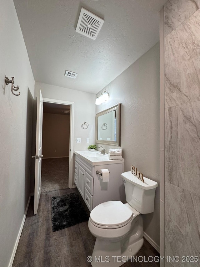 bathroom featuring wood-type flooring, toilet, a textured ceiling, and vanity