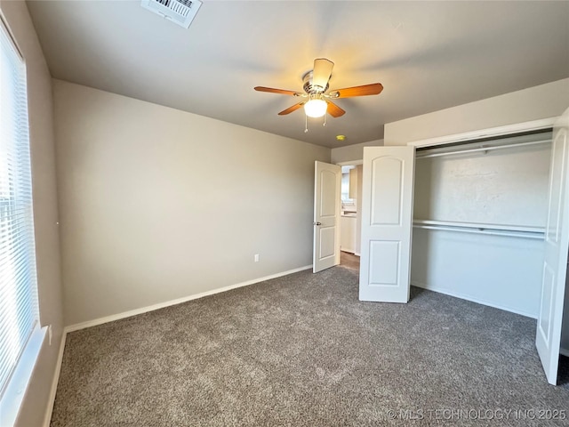 unfurnished bedroom with ceiling fan, a closet, and dark colored carpet