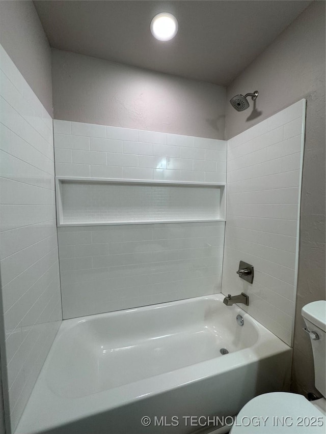 bathroom featuring tiled shower / bath combo and toilet