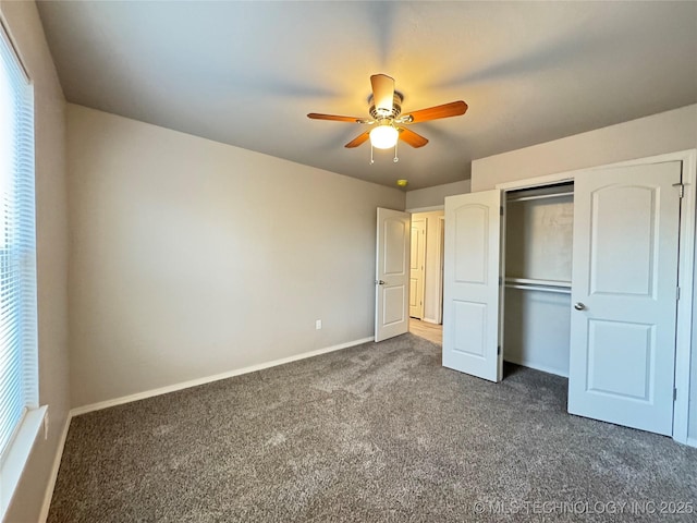 unfurnished bedroom with ceiling fan, a closet, and dark colored carpet