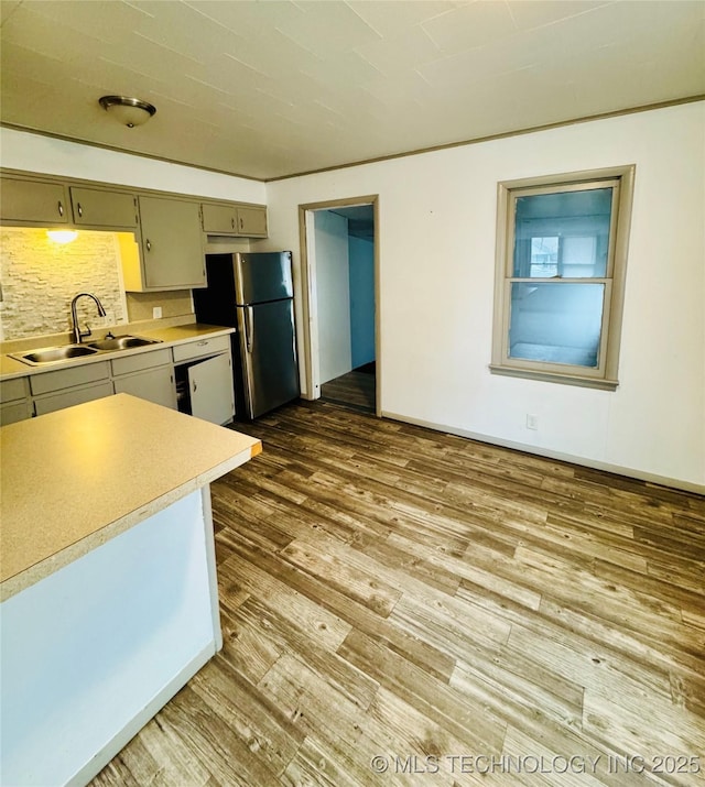 kitchen with sink, stainless steel refrigerator, hardwood / wood-style floors, white dishwasher, and tasteful backsplash