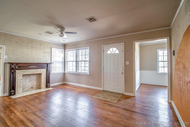 entrance foyer featuring wood-type flooring, ornamental molding, ceiling fan, and a fireplace