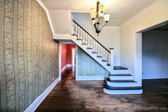 stairs featuring hardwood / wood-style floors, crown molding, and a notable chandelier