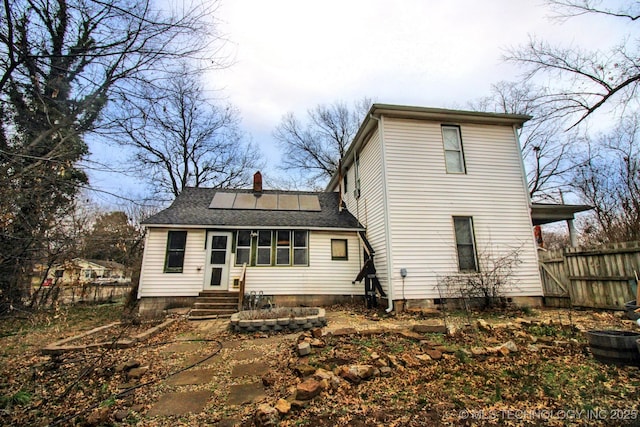 rear view of property featuring solar panels