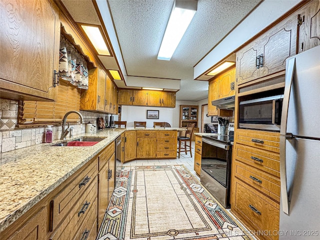 kitchen with light tile patterned flooring, sink, tasteful backsplash, a textured ceiling, and appliances with stainless steel finishes