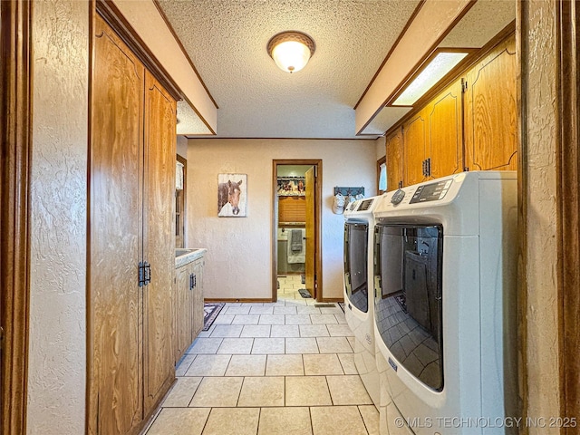 laundry room featuring cabinets, light tile patterned floors, a textured ceiling, and washer and clothes dryer