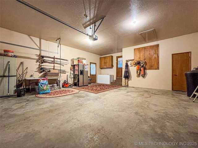 garage with a garage door opener and stainless steel refrigerator with ice dispenser