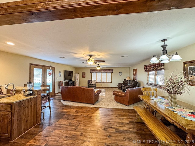 living room featuring a healthy amount of sunlight, dark hardwood / wood-style floors, sink, and a textured ceiling