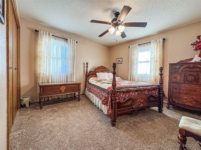 bedroom with ceiling fan, carpet floors, and a textured ceiling