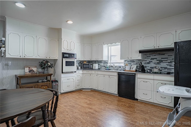 kitchen with white cabinetry, light hardwood / wood-style floors, decorative backsplash, and black appliances