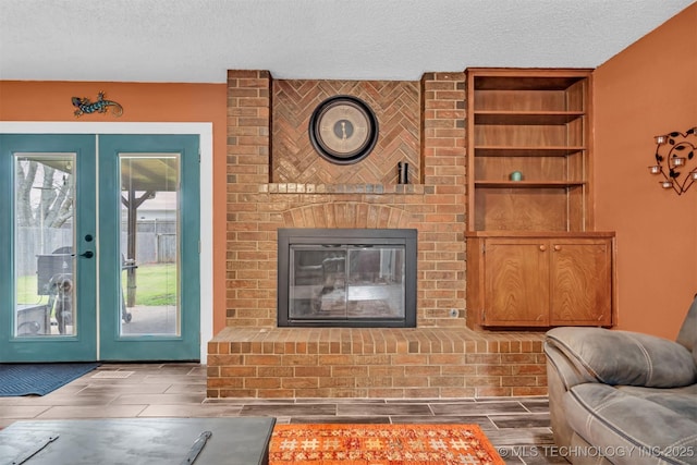 living room featuring a brick fireplace, french doors, and a textured ceiling