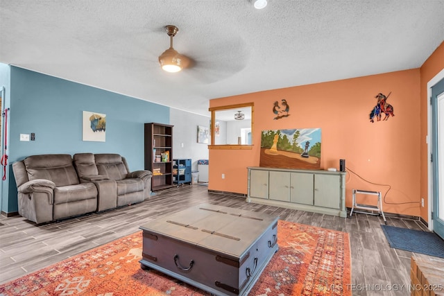 living room with ceiling fan, hardwood / wood-style flooring, and a textured ceiling