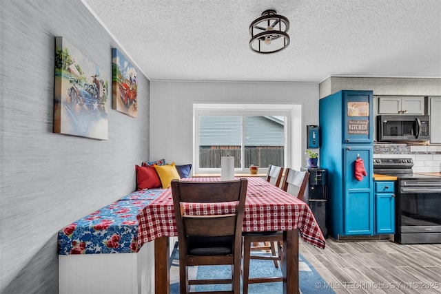 dining area featuring light hardwood / wood-style floors and a textured ceiling