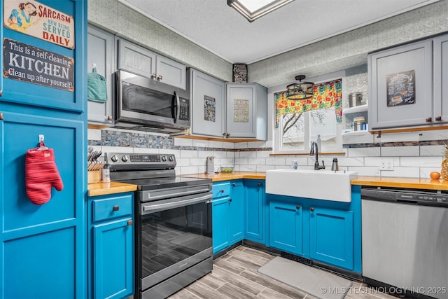 kitchen with sink, wooden counters, appliances with stainless steel finishes, tasteful backsplash, and a textured ceiling