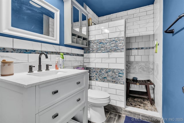 bathroom with tile walls, vanity, and toilet