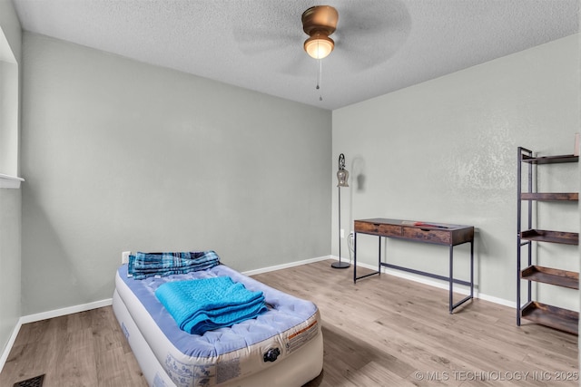 living area with ceiling fan, a textured ceiling, and light hardwood / wood-style floors