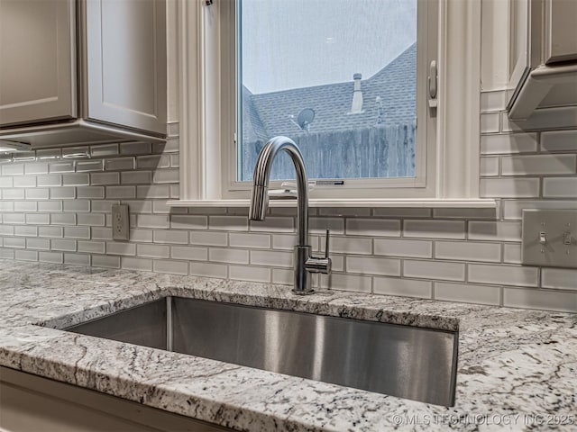 room details with decorative backsplash, sink, and light stone counters