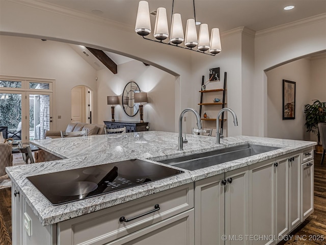 kitchen with an island with sink, sink, hanging light fixtures, and dark hardwood / wood-style flooring