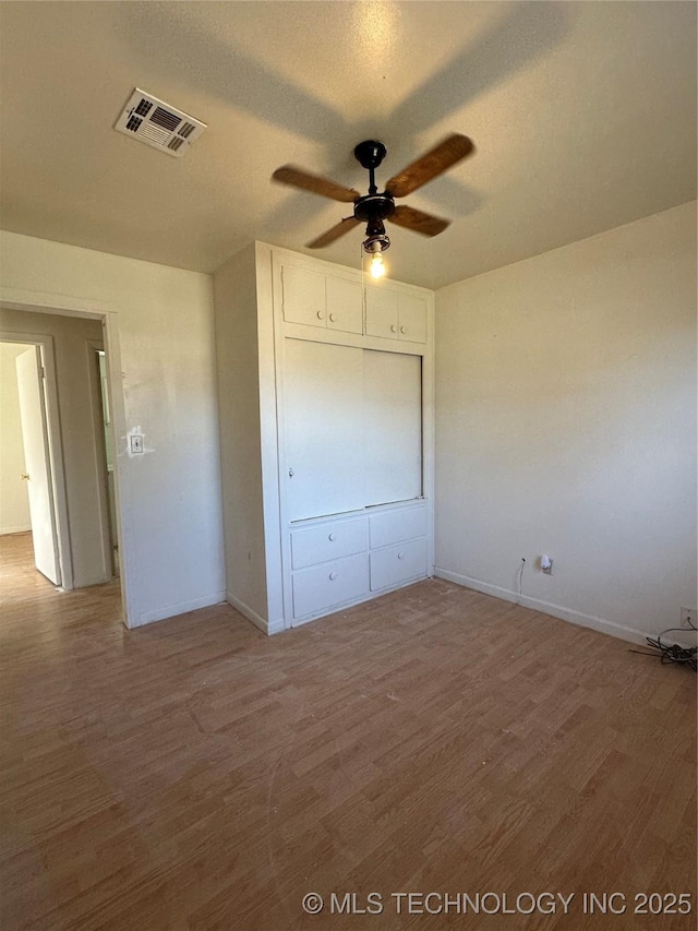 unfurnished bedroom featuring ceiling fan, hardwood / wood-style floors, and a closet