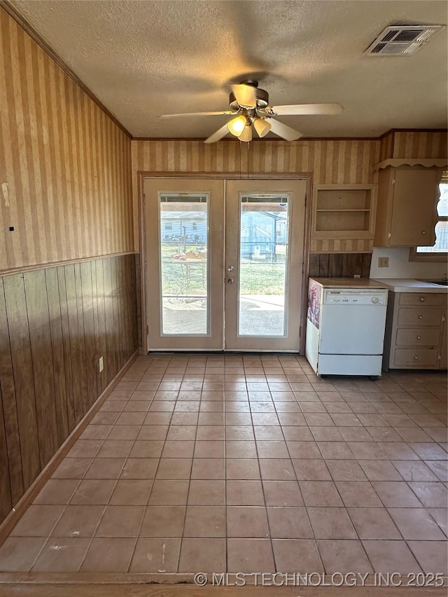 kitchen featuring wood walls, a textured ceiling, light tile patterned floors, dishwasher, and ceiling fan