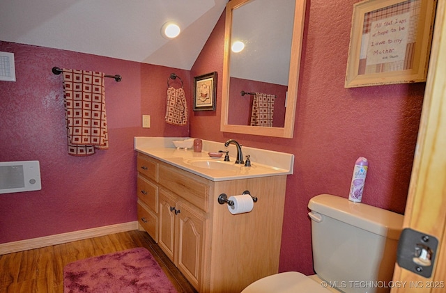 bathroom with wood-type flooring, lofted ceiling, vanity, and toilet