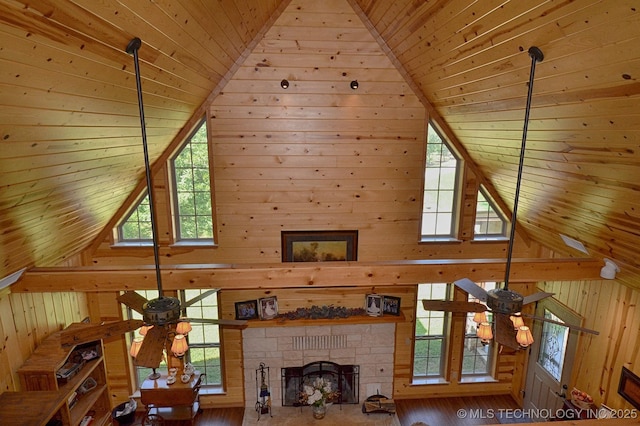 unfurnished living room with wood ceiling, ceiling fan, a stone fireplace, and high vaulted ceiling