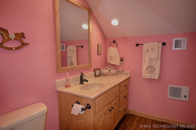 bathroom with vaulted ceiling, wood-type flooring, vanity, and toilet