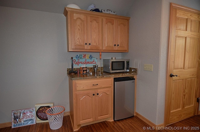 kitchen with fridge, light brown cabinetry, dark wood-type flooring, and stone counters