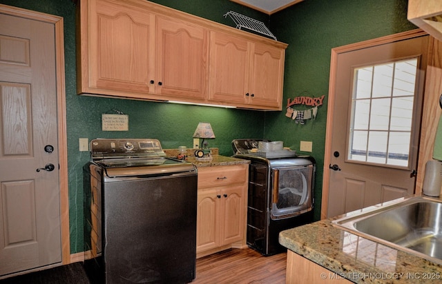 laundry room featuring independent washer and dryer, sink, cabinets, and light wood-type flooring