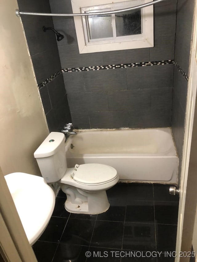 bathroom with tile patterned floors, toilet, and tiled shower / bath combo