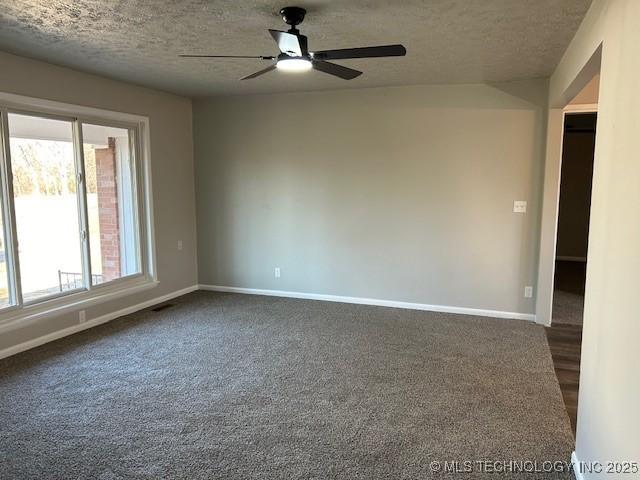 unfurnished room with ceiling fan, dark carpet, and a textured ceiling