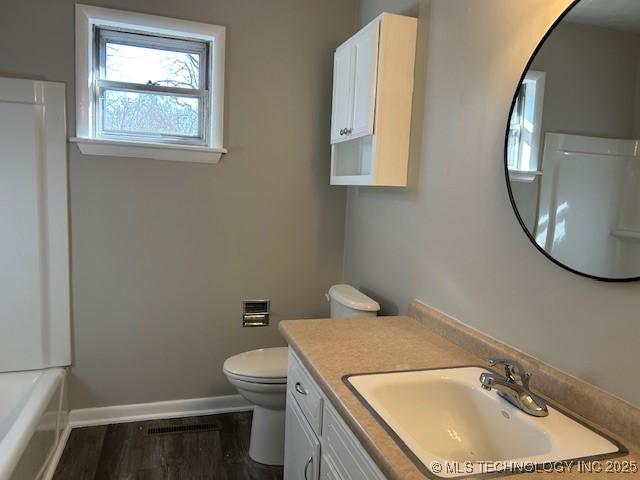 bathroom with wood-type flooring, vanity, and toilet