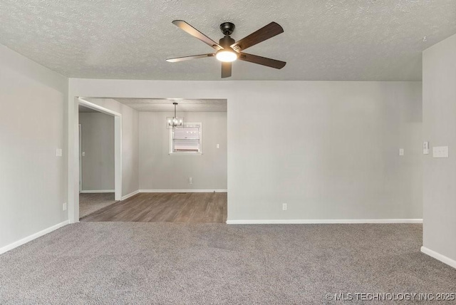 carpeted spare room featuring ceiling fan with notable chandelier and a textured ceiling