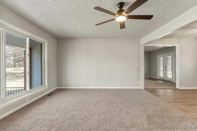 carpeted spare room with ceiling fan and a textured ceiling