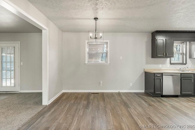 interior space with hardwood / wood-style floors, a textured ceiling, decorative light fixtures, stainless steel dishwasher, and a chandelier