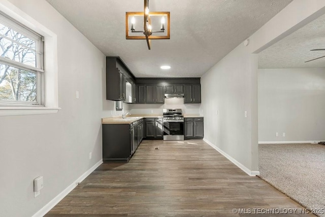 kitchen with dark hardwood / wood-style flooring, stainless steel range, decorative light fixtures, and a textured ceiling