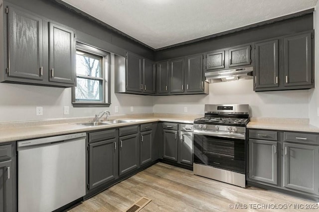 kitchen featuring sink, light wood-type flooring, a textured ceiling, and appliances with stainless steel finishes