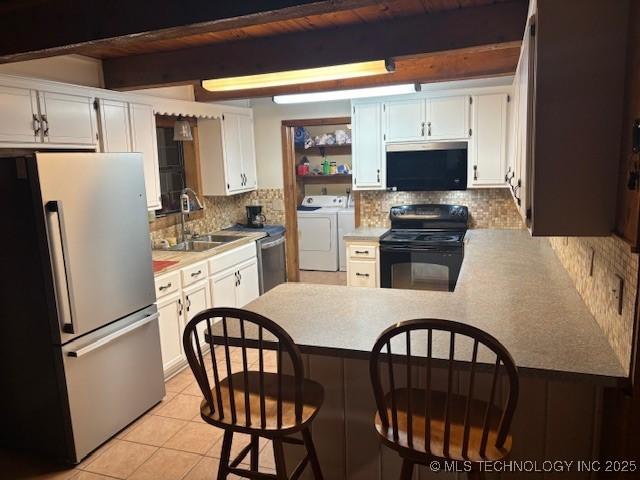 kitchen with white cabinets, electric range, washing machine and clothes dryer, and stainless steel fridge