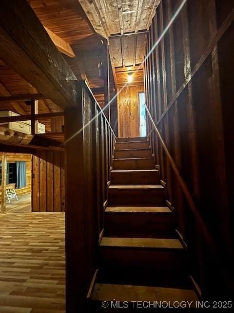 staircase featuring hardwood / wood-style floors, wooden walls, and wooden ceiling