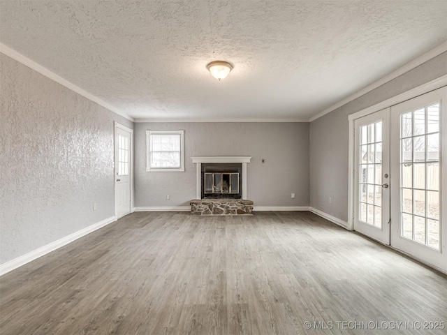 unfurnished living room with wood-type flooring, ornamental molding, french doors, and a textured ceiling