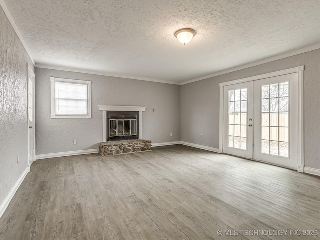 unfurnished living room with hardwood / wood-style floors, a stone fireplace, and plenty of natural light