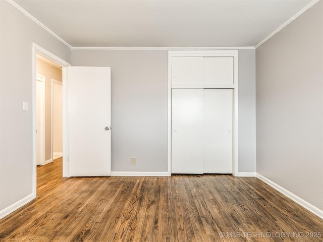 unfurnished bedroom with a closet, crown molding, and dark hardwood / wood-style floors