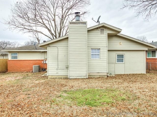 rear view of house featuring central AC and a lawn