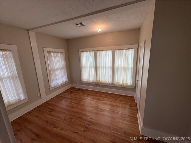 empty room featuring dark wood-type flooring and a textured ceiling