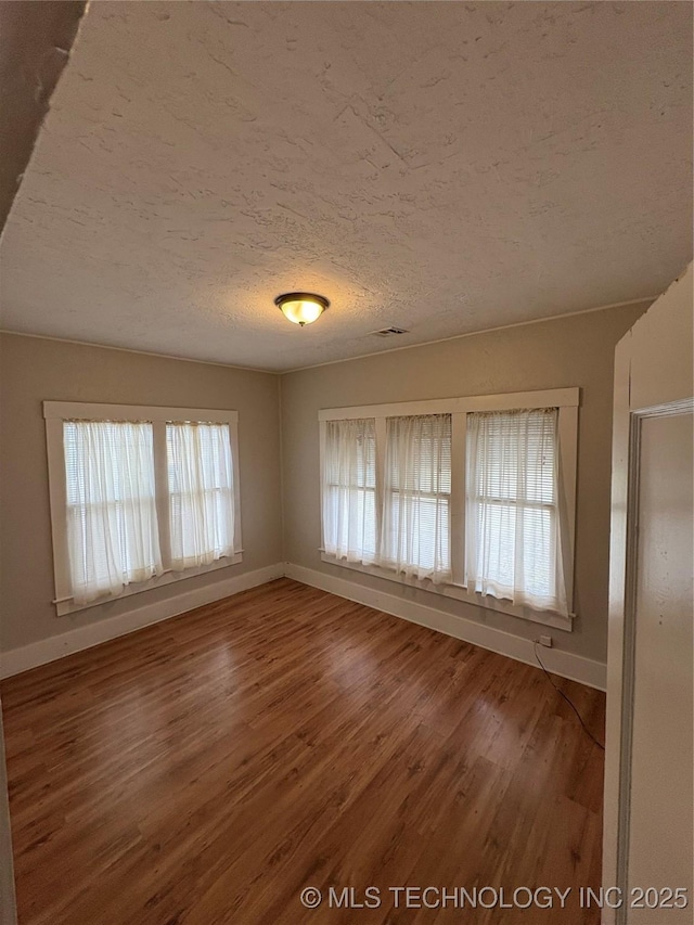 unfurnished room with hardwood / wood-style floors and a textured ceiling