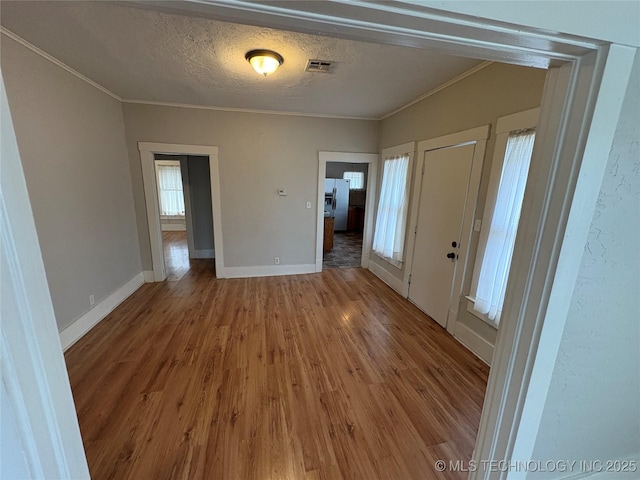 interior space with ornamental molding, wood-type flooring, and a textured ceiling