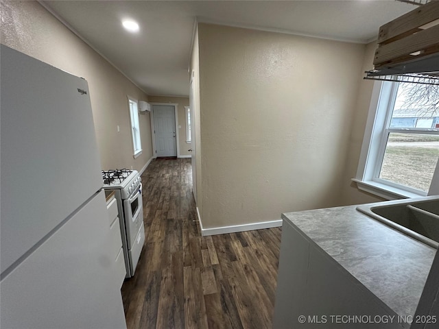 kitchen featuring dark wood-type flooring, white appliances, and sink