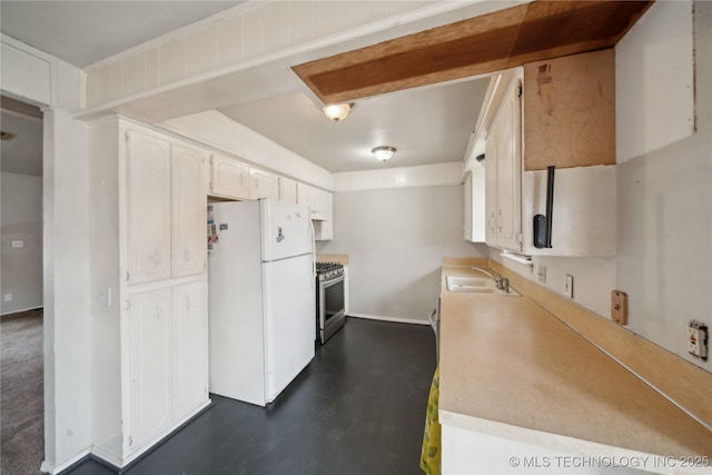 kitchen with sink, stainless steel gas range oven, white cabinetry, and white refrigerator